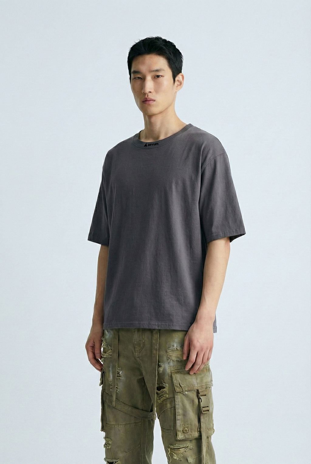 Man wearing a gray t-shirt and green cargo pants on a light gray background