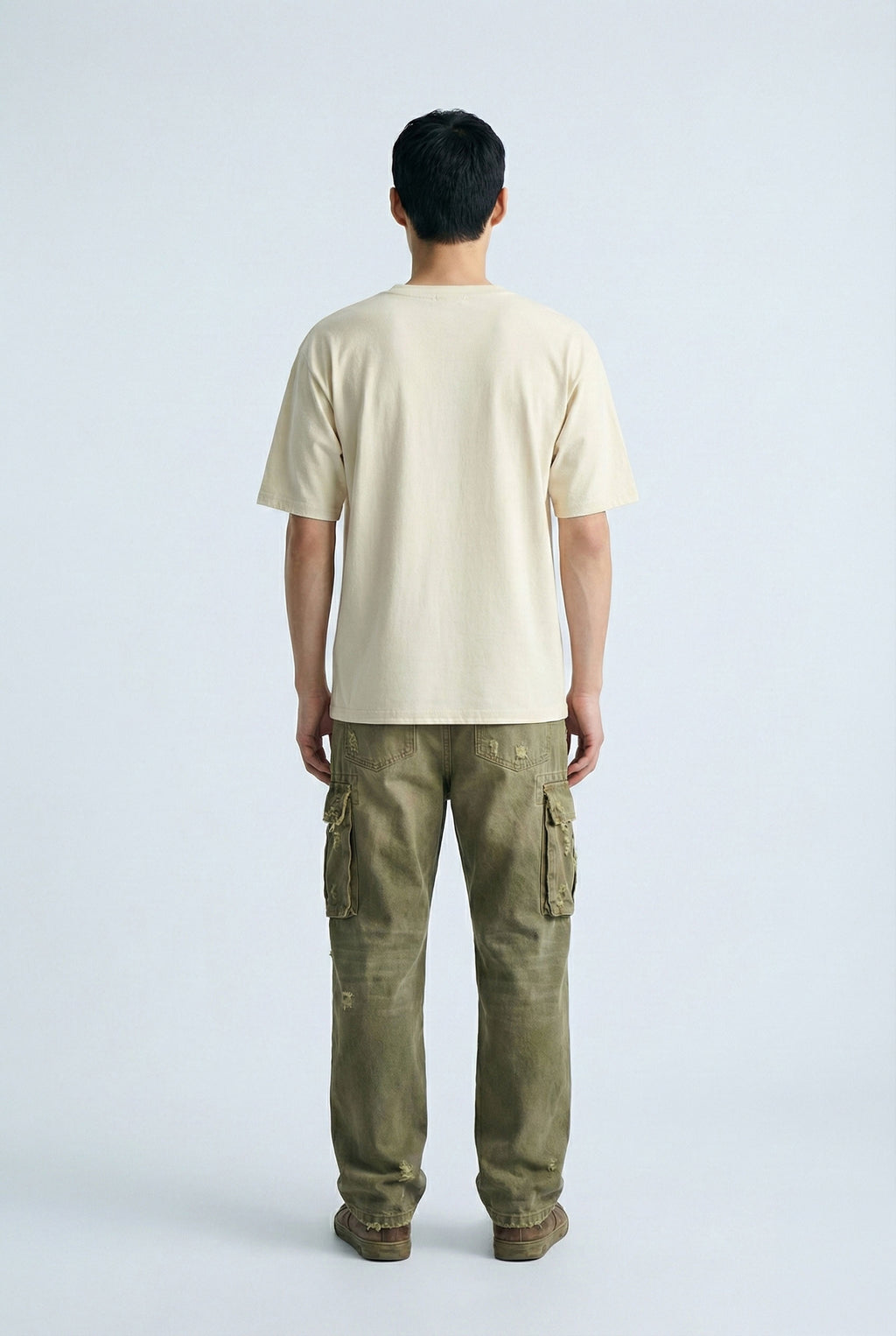 Person wearing a beige t-shirt and green cargo pants on a white background