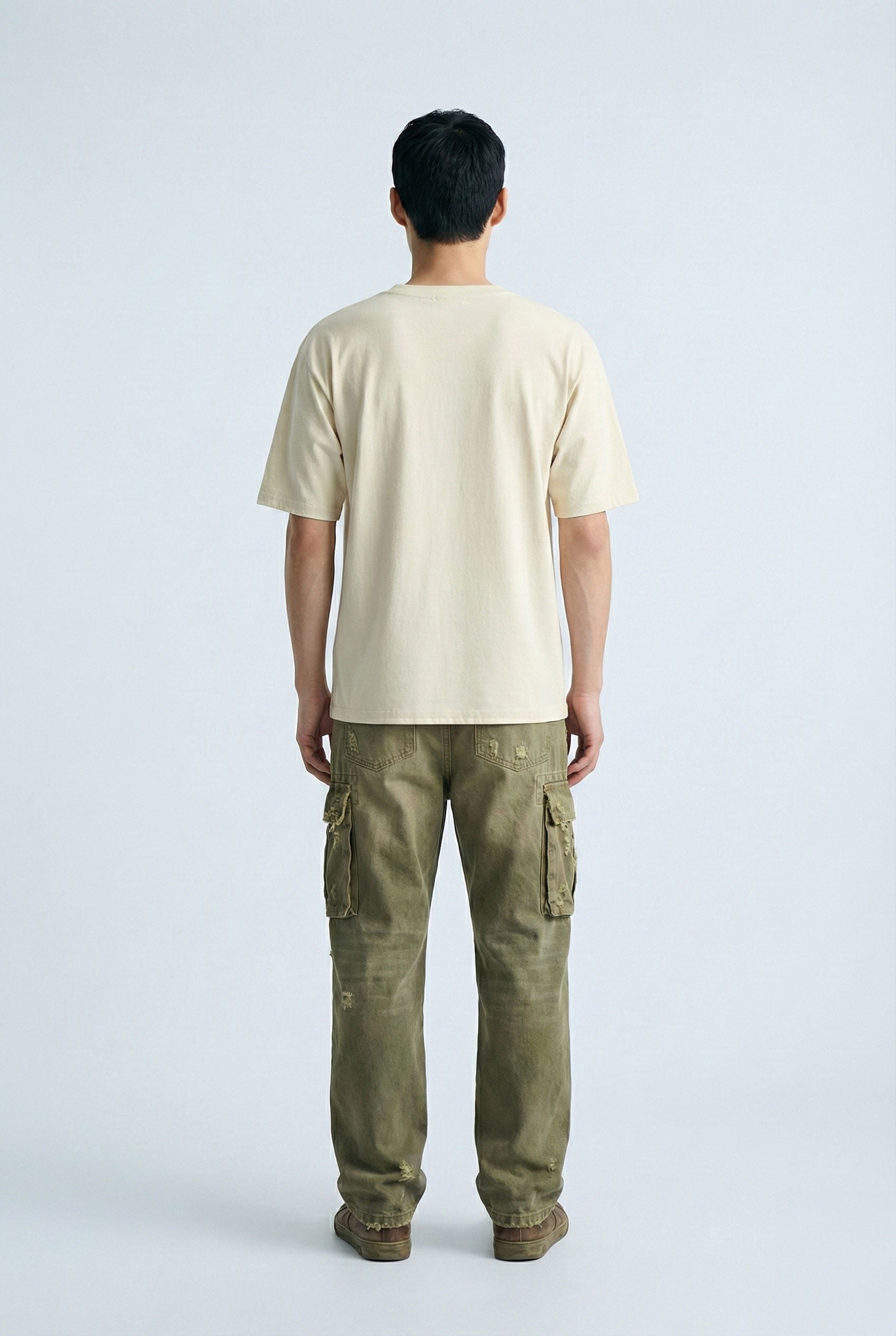Person wearing a beige t-shirt and green cargo pants on a white background
