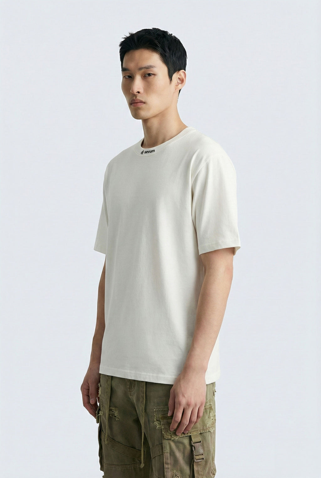 Man wearing a white t-shirt and green pants on a light gray background