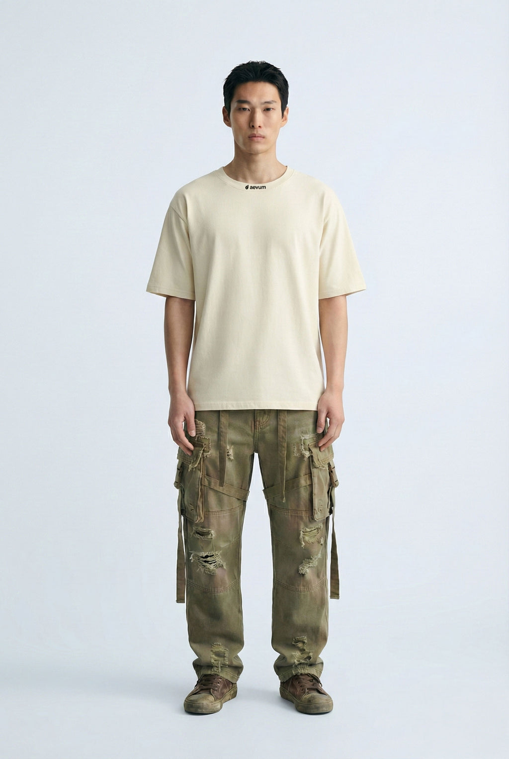 Person wearing a beige t-shirt and camouflage cargo pants on a white background