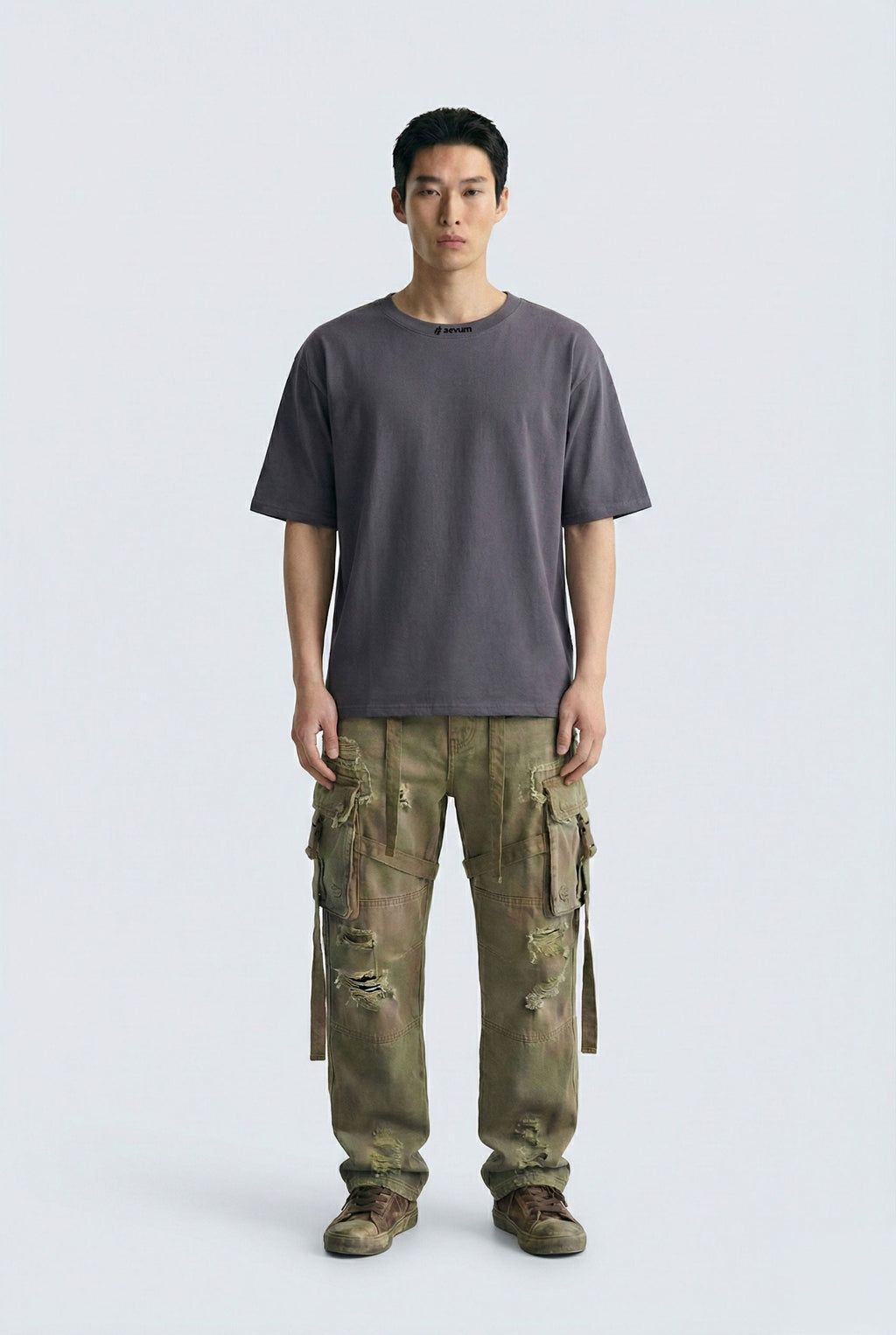 Person wearing a gray t-shirt and camouflage pants on a white background