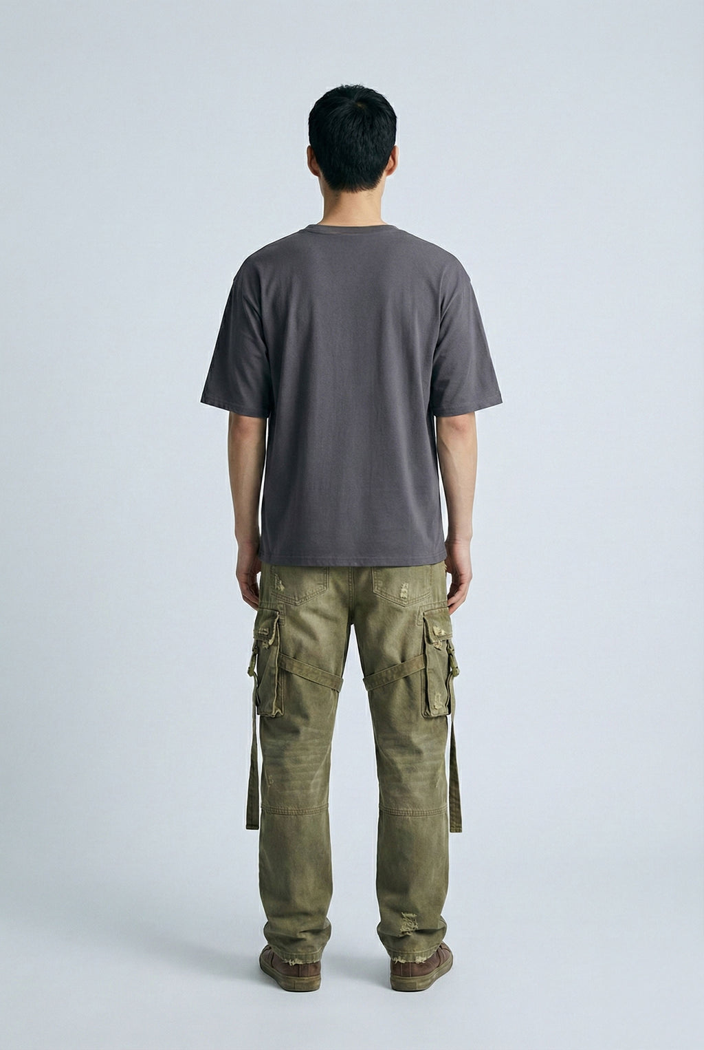 Person wearing a gray t-shirt and green cargo pants on a white background