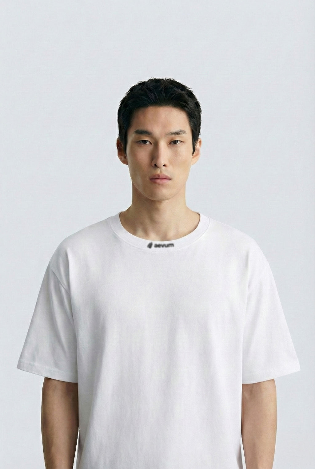 Person wearing a plain white t-shirt against a light gray background
