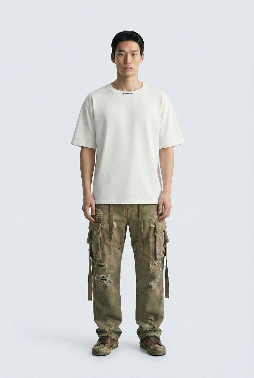 Person wearing a white t-shirt and green cargo pants on a light gray background