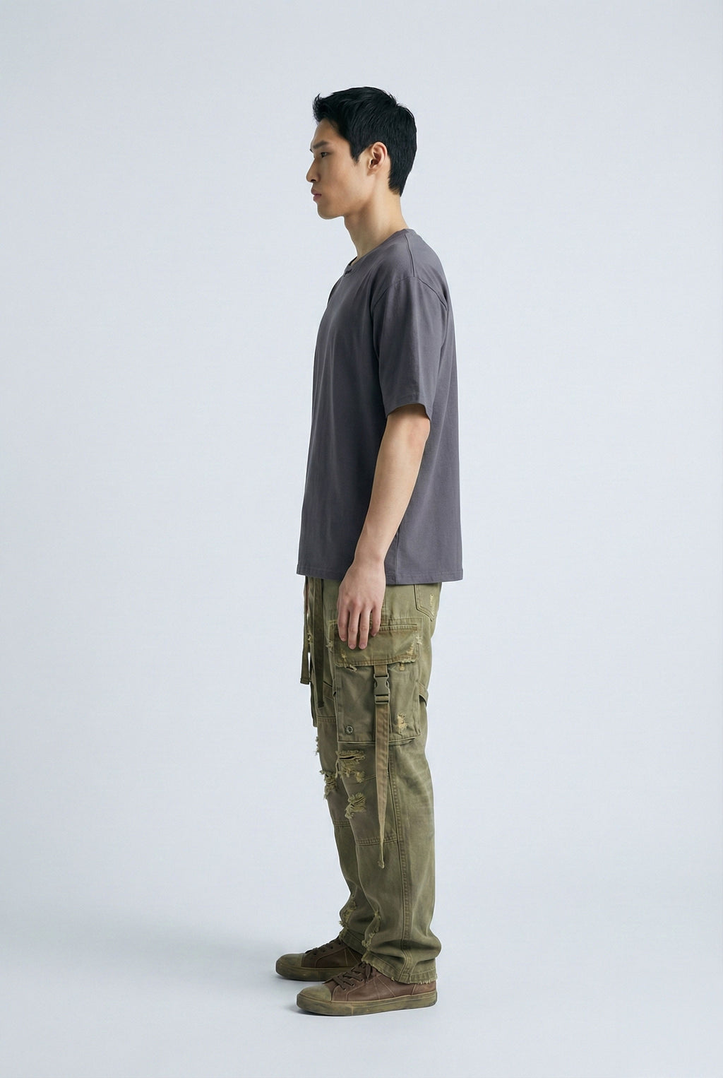 Person wearing a gray t-shirt and green cargo pants on a white background
