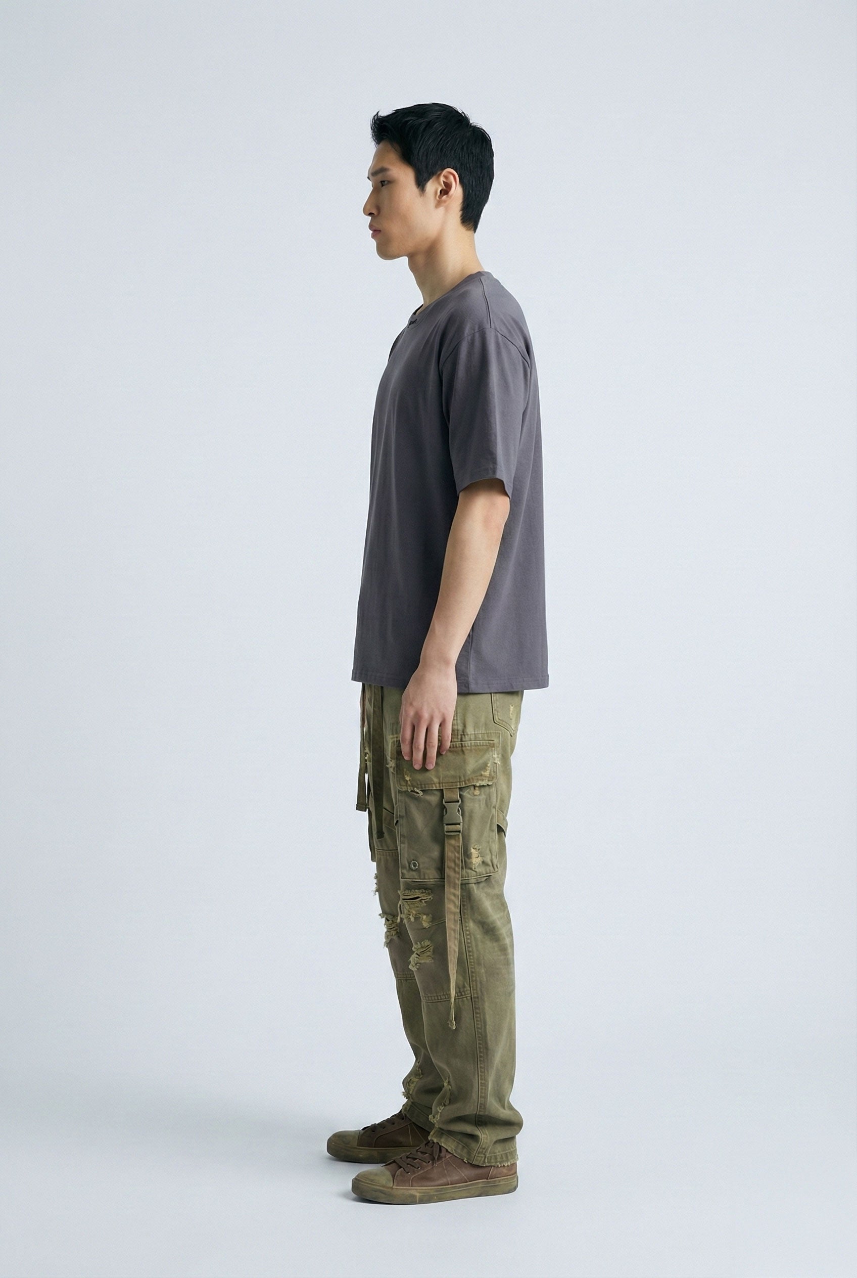 Person wearing a gray t-shirt and green cargo pants on a white background